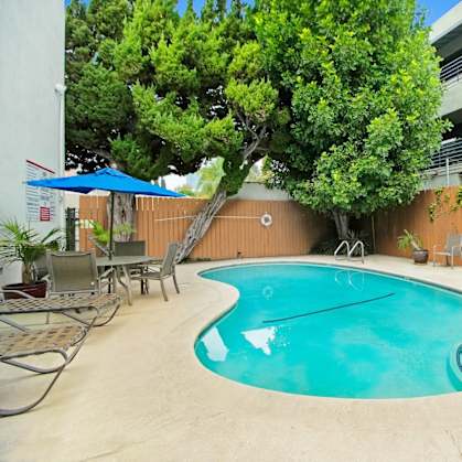 a swimming pool with chairs and umbrellas in front of a building