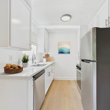 A kitchen with white cabinets and a black refrigerator.