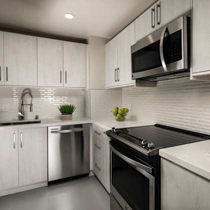 A modern kitchen with a black stove top oven and white cabinets.