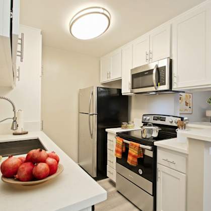 A kitchen with white cabinets and black appliances.