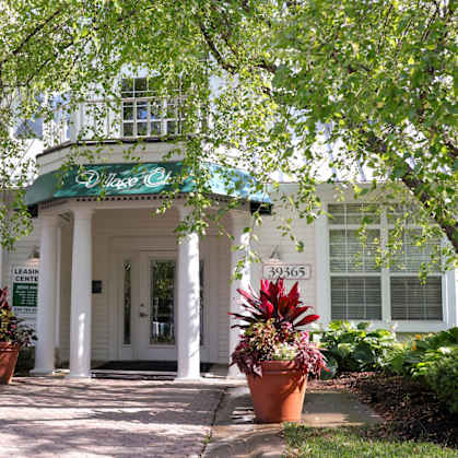 a white building with potted plants in front of it at Village Club of Farmington Hills, Farmington Hills, MI