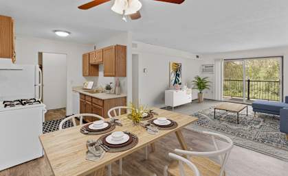a dining area with a wooden table and chairs and a kitchen in the background