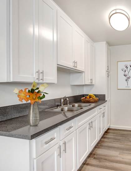 A kitchen with white cabinets and a black refrigerator.