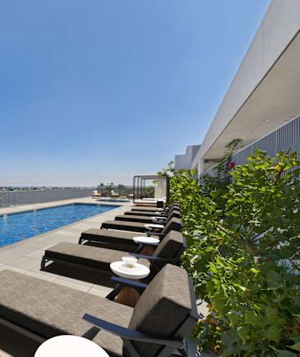 A row of sun loungers are on the edge of a swimming pool.