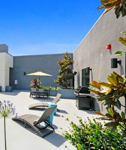a patio with chairs and a table and an umbrella