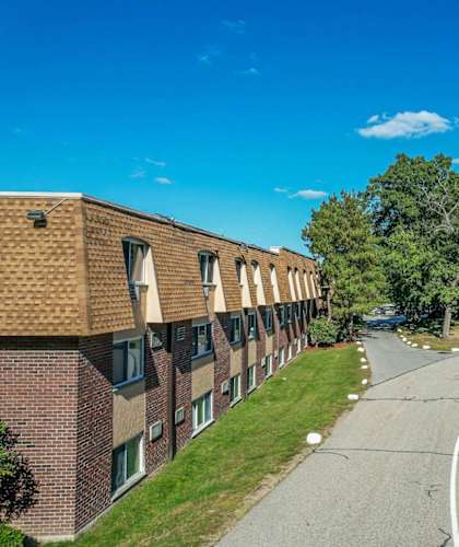 A road with a white line in the middle runs between two rows of apartment buildings.