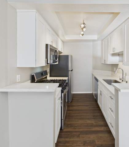 A kitchen with white cabinets and a black refrigerator.