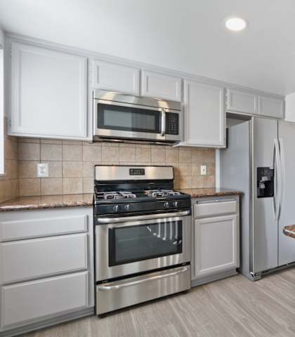 A kitchen with a stove, oven, refrigerator, and microwave.