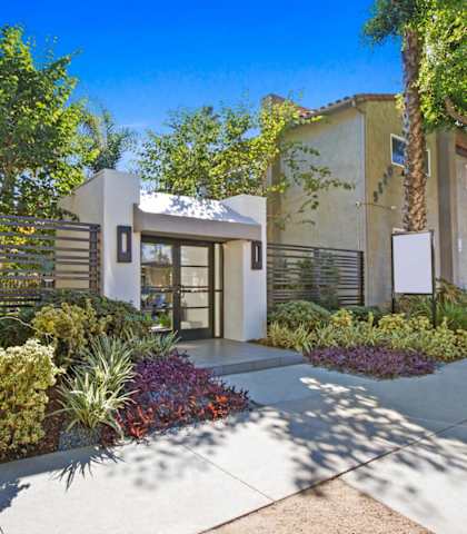 a house with a sidewalk and trees in front of it
