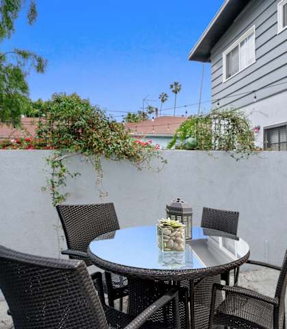 a patio with a table and chairs in front of a house