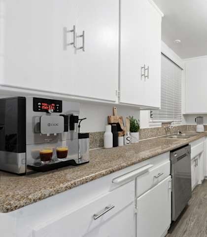 a kitchen with white cabinets and granite counter tops and stainless steel appliances