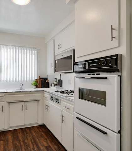 an empty kitchen with white appliances and white cabinets