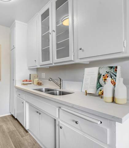 A kitchen with white cabinets and a fridge.