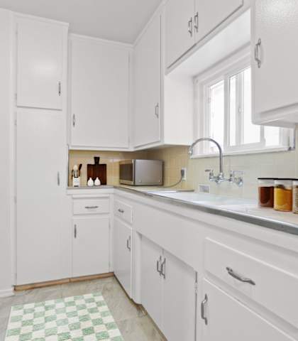 a white kitchen with a sink and a window