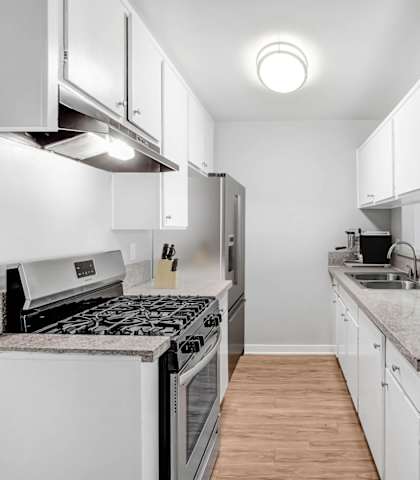 a renovated kitchen with white cabinets and stainless steel appliances