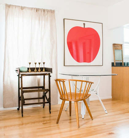a dining room with a table and chairs and a painting of an apple