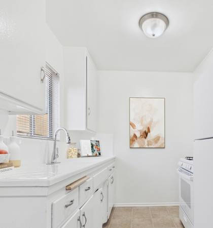 A white kitchen with a bowl of fruit on the counter.