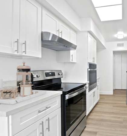 a white kitchen with black appliances and white cabinets