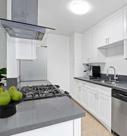 a white kitchen with stainless steel appliances and white cabinets