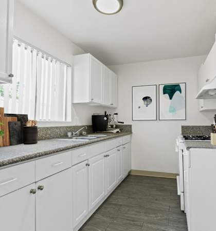 a white kitchen with granite counter tops and white cabinets