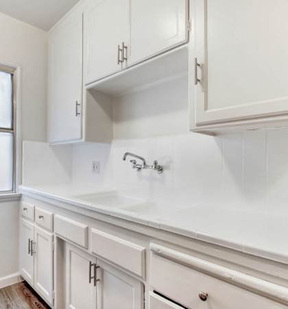 a kitchen with white cabinets and a window