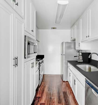 a kitchen with white cabinets and a wood floor