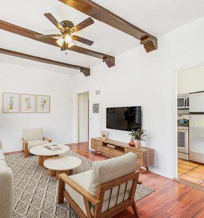 A living room with a wooden ceiling fan and a television.