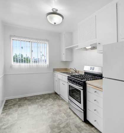 an empty kitchen with white cabinets and white appliances