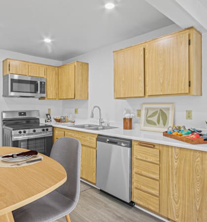 a kitchen and dining area with wooden cabinets and stainless steel appliances