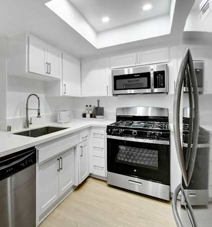 a white kitchen with stainless steel appliances and white counter tops