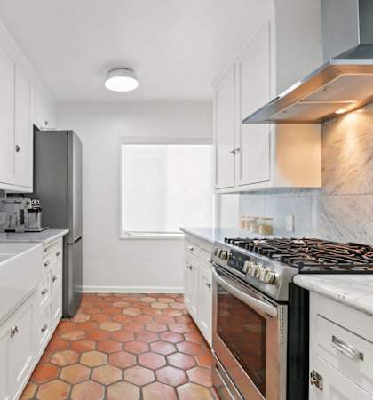 a kitchen with white cabinets and a stove and a window