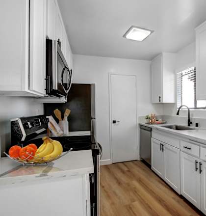 a kitchen with white cabinets and a bowl of fruit on the counter