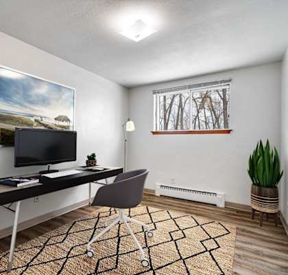 A room with a desk, chair, and a painting on the wall.