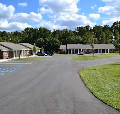 A parking lot with a building in the background and a car parked in the lot.