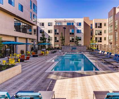 a swimming pool at an apartment complex with lounge chairs