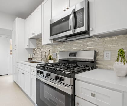 A modern kitchen with white cabinets and a black stove top.