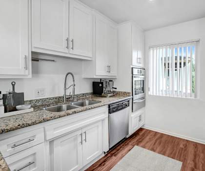 a kitchen with white cabinets and black counter tops and a window