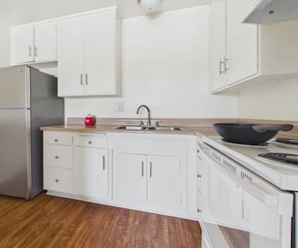 A kitchen with white cabinets and a stainless steel refrigerator.