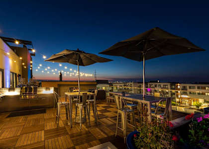 a rooftop bar with tables and chairs and umbrellas