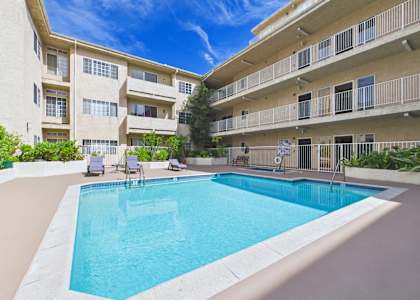 A swimming pool in front of a building with a blue sky in the background.