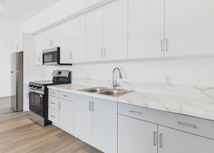 A modern kitchen with white cabinets and a marble countertop.