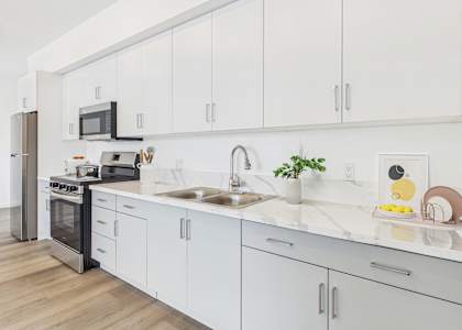 A modern kitchen with white cabinets and a marble countertop.