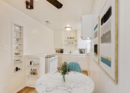 A kitchen with a marble table and a ceiling fan.
