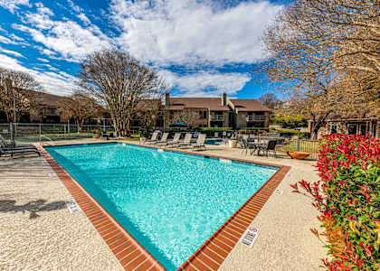 a swimming pool with chairs and a house in the background