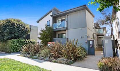 an apartment building with a sidewalk and plants in front of it  at The Aster, California, 90024