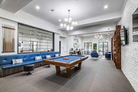 A room with a pool table and a bar area.