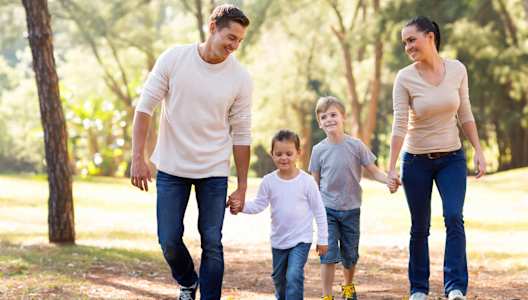A Family of Four is Walking Hand in Hand Through a Wooded Area at Cottages at Beltmill Apartments, Saginaw, TX, 76131