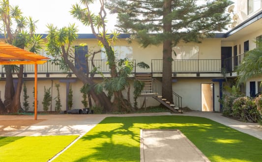 the courtyard of a building with a lawn and palm trees