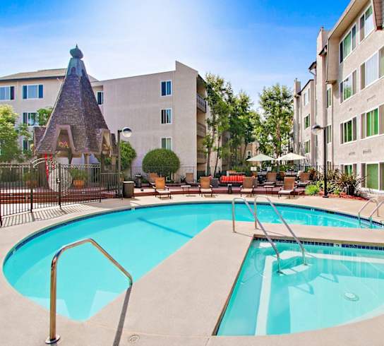 A large swimming pool in front of a building with a small tower.