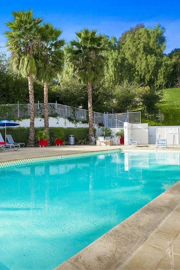 a swimming pool with palm trees and chairs around it